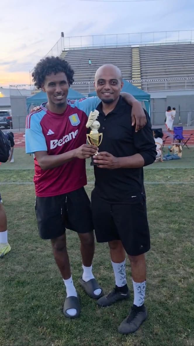 Ethio Unity player and coach holding a soccer trophy